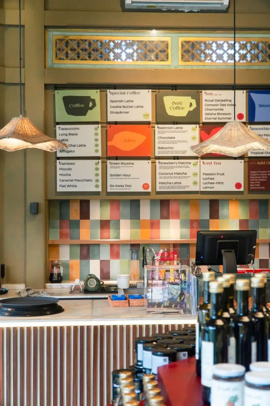 Coffee shop counter with an illustrated menu board and colorful tiled wall
