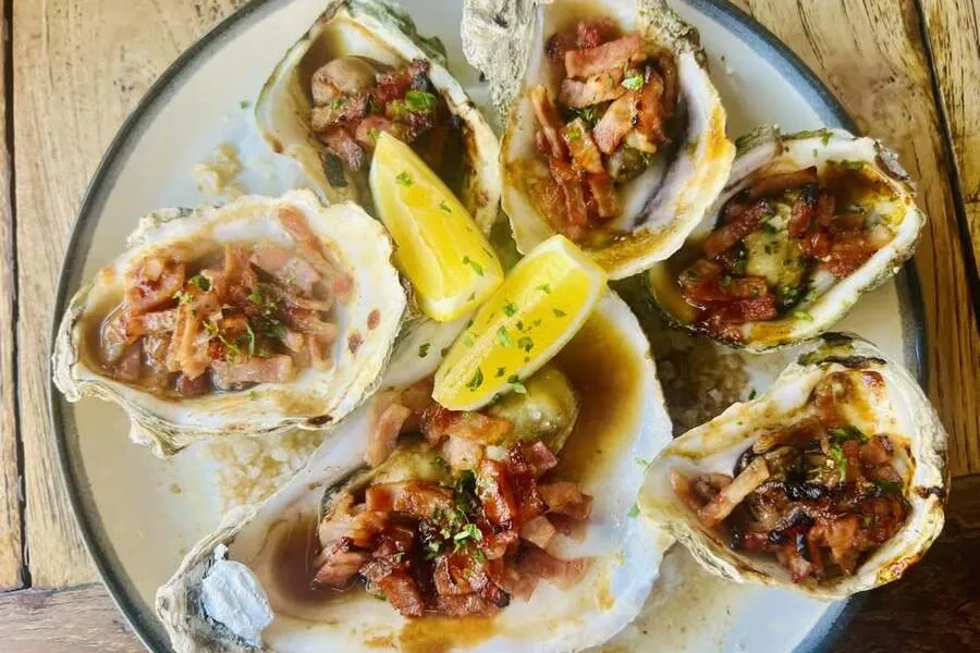 Platter of baked oysters topped with bacon and lemon